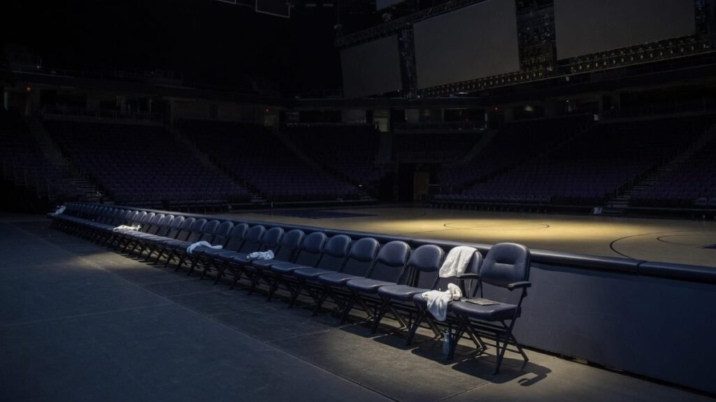 An empty coach's chair at the end of a basketball bench in a dark arena